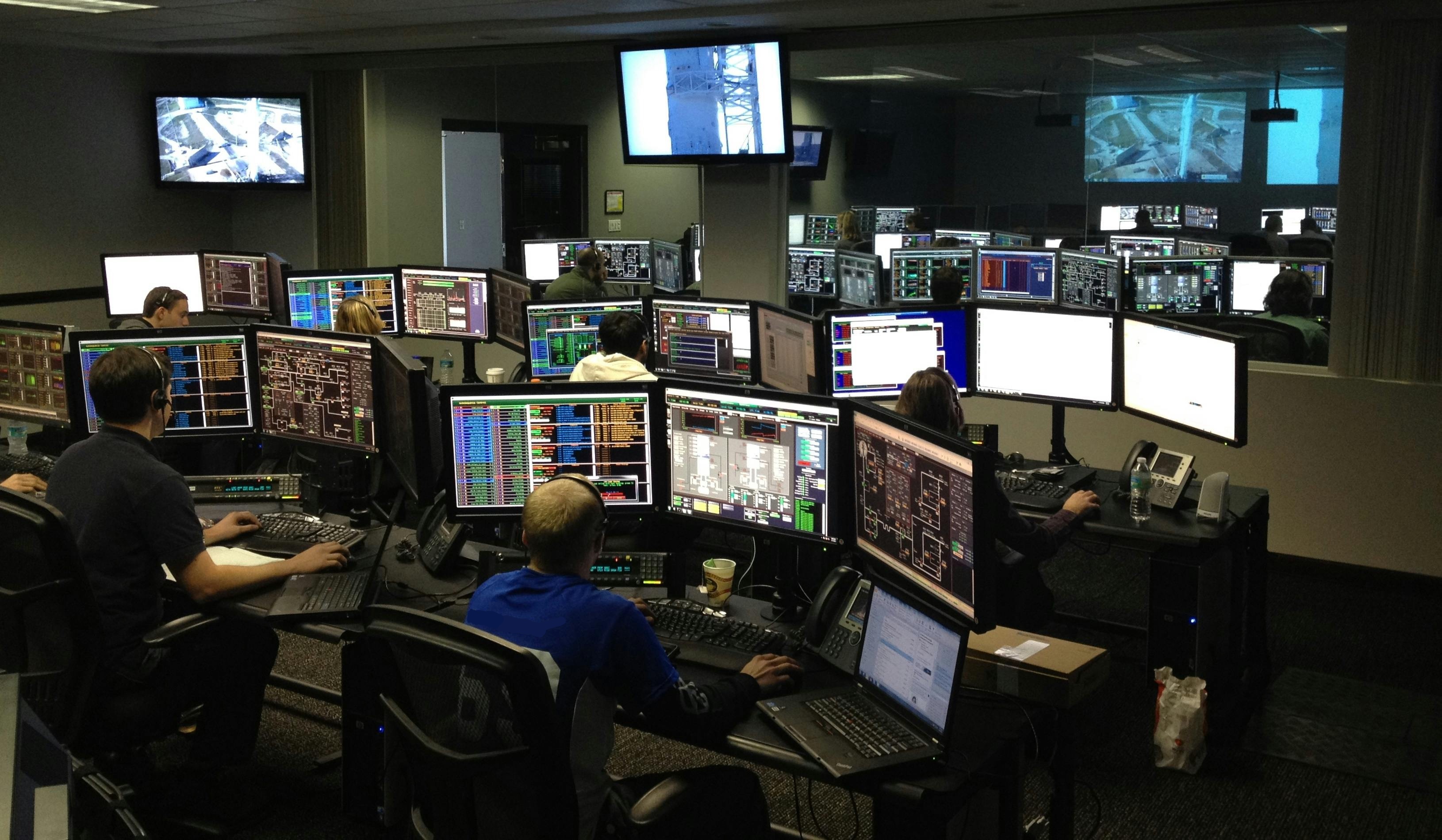 Operations center with analysts reviewing multi-screen video and data feeds.
