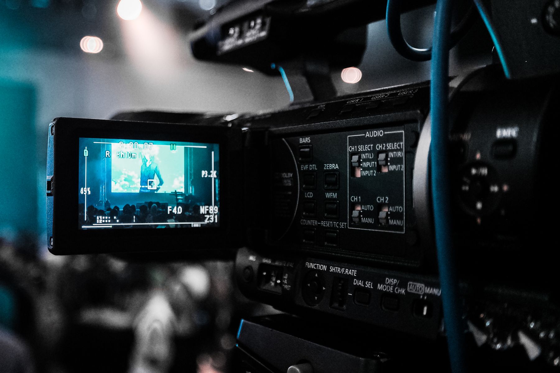 Professional video camera capturing a live stage feed on its LCD.
